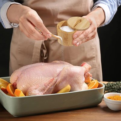 homme prenant le pot a epice et saupoudrant un poulet